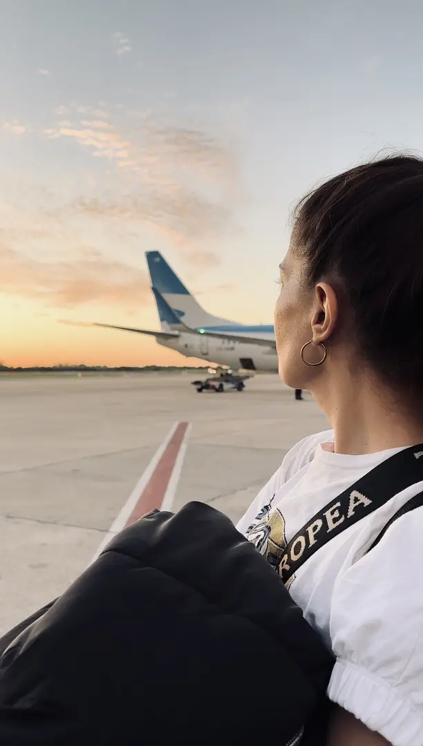 Reisende blickt am Flughafen auf ein Flugzeug in der Abendsonne